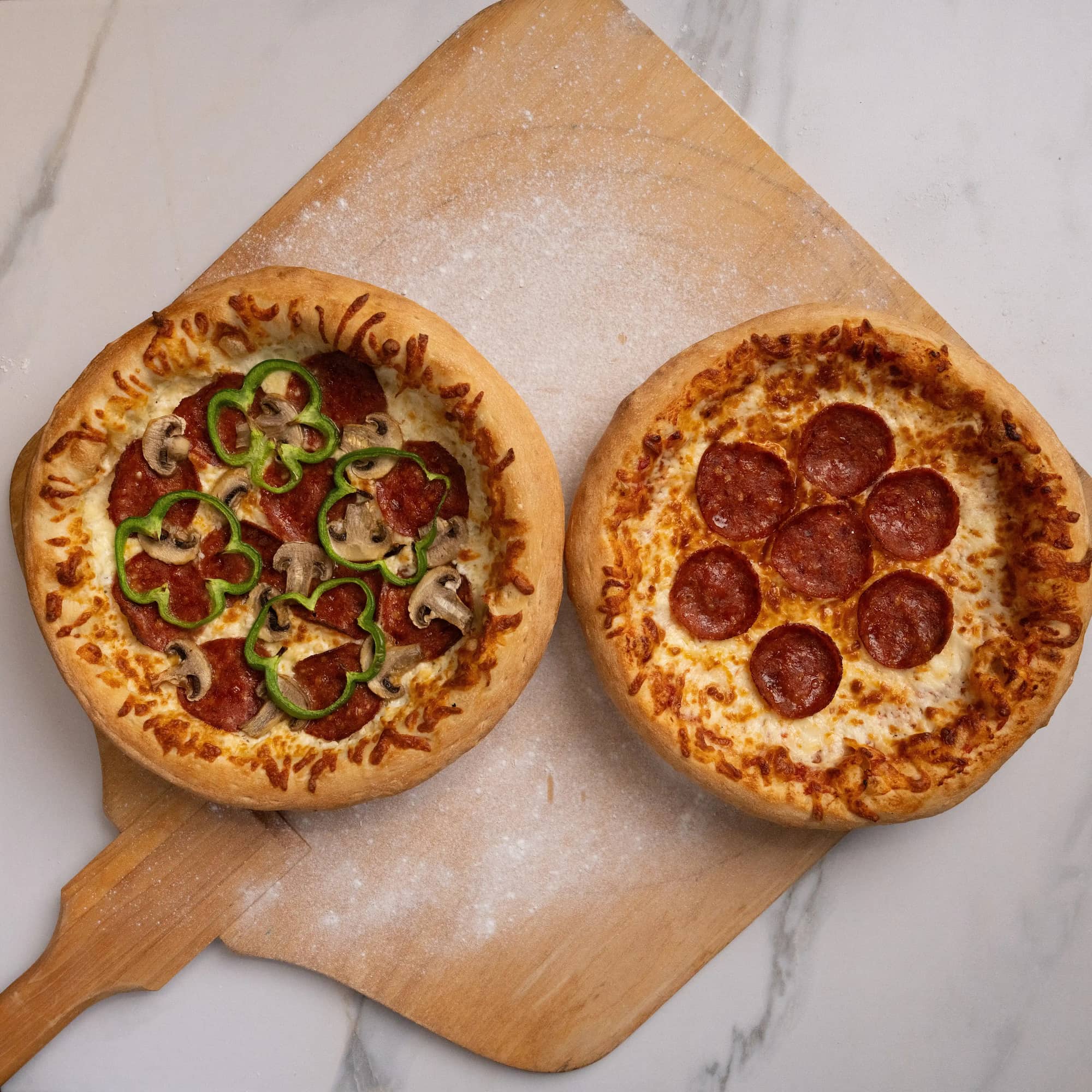 2 pizzas sur planche en bois